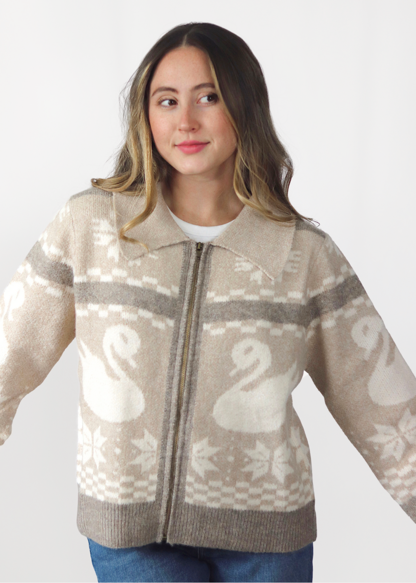 Woman wearing a beige sweater with a swan pattern on a white background