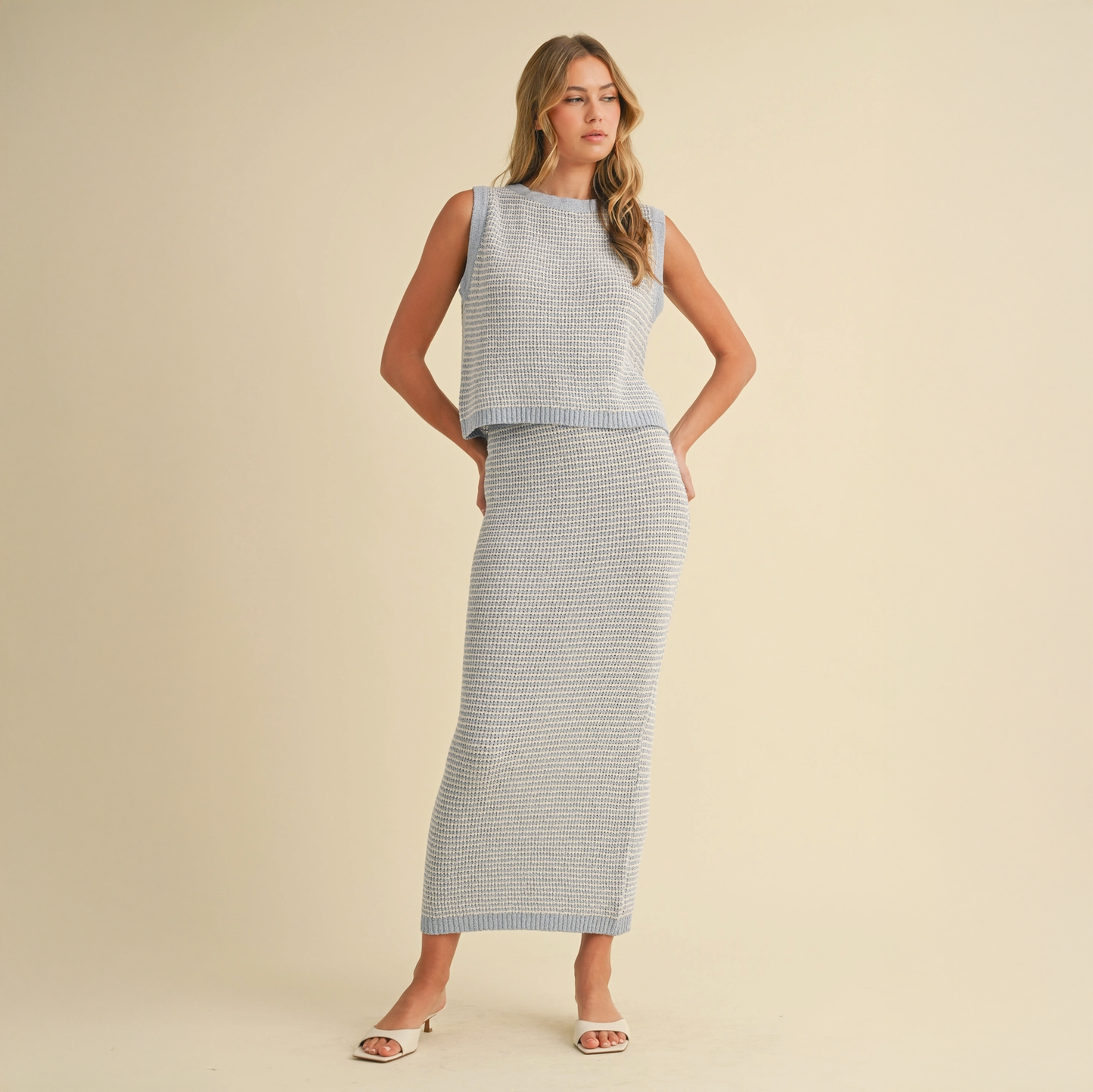 A woman wearing a sleeveless baby blue and cream striped top with a matching maxi skirt.