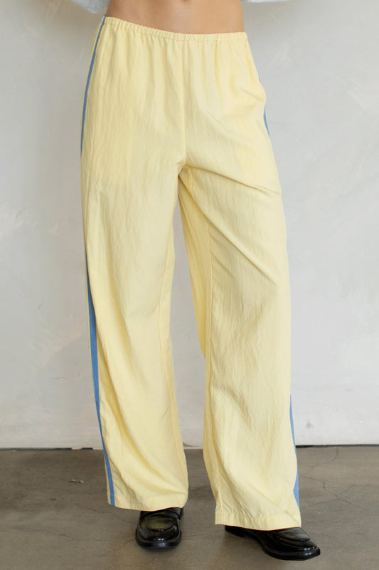 Light yellow pants with blue stripes worn by a person against a plain background