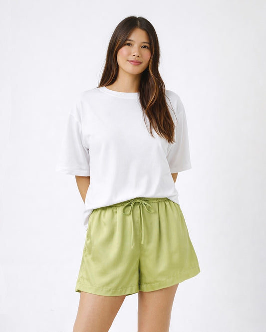 Woman wearing a white top and light green shorts on a white background