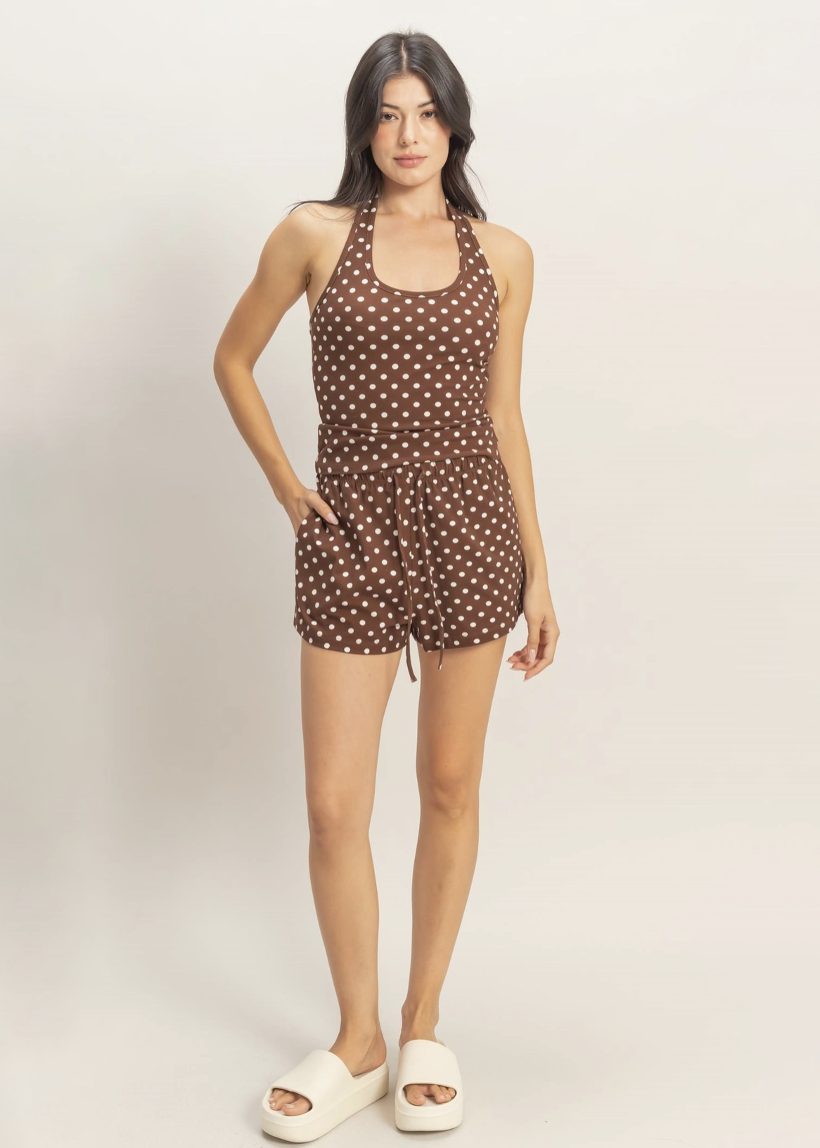 Woman wearing a brown polka dot romper on a white background