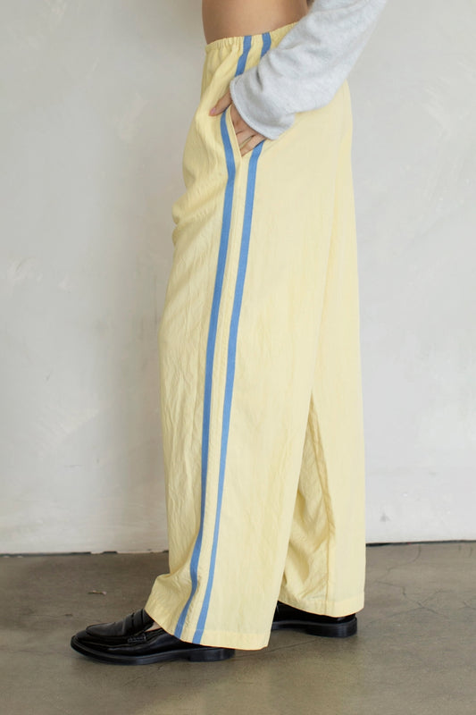 Person wearing yellow pants with blue stripes against a plain background