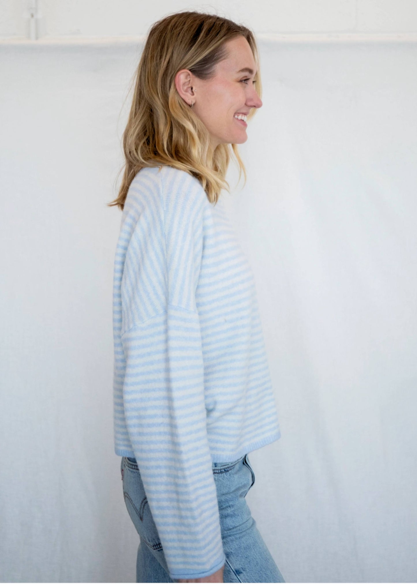Woman wearing a light blue striped sweater against a white background