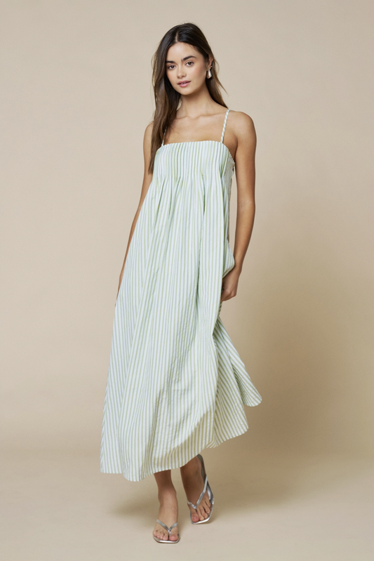 Woman wearing a light green striped dress against a beige background