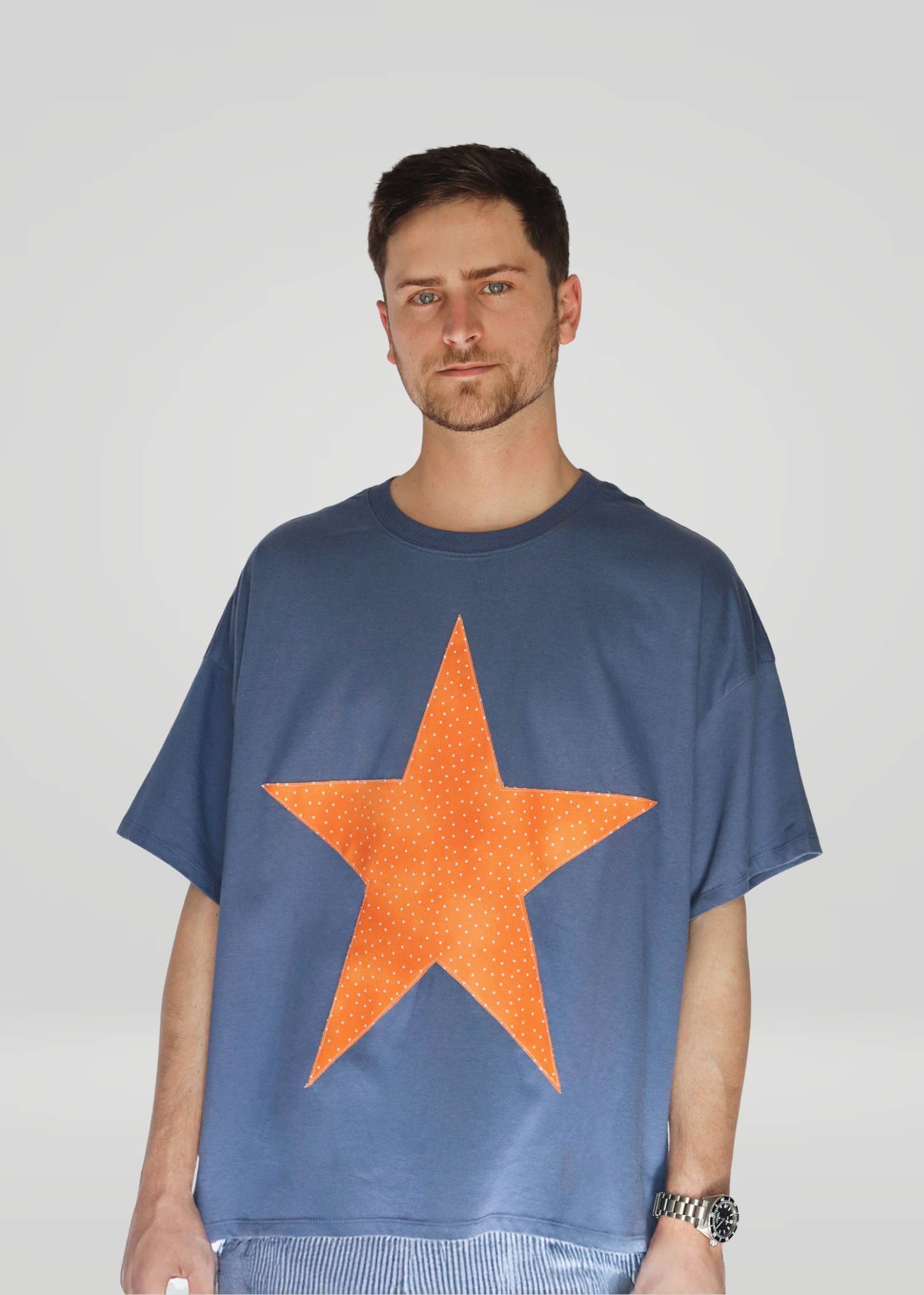 Man wearing a blue t-shirt with an orange star on a plain background