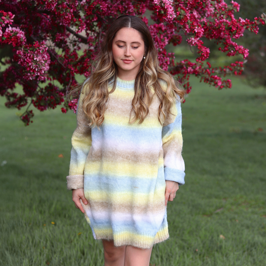 Young girl in a striped dress standing in front of a flowering tree