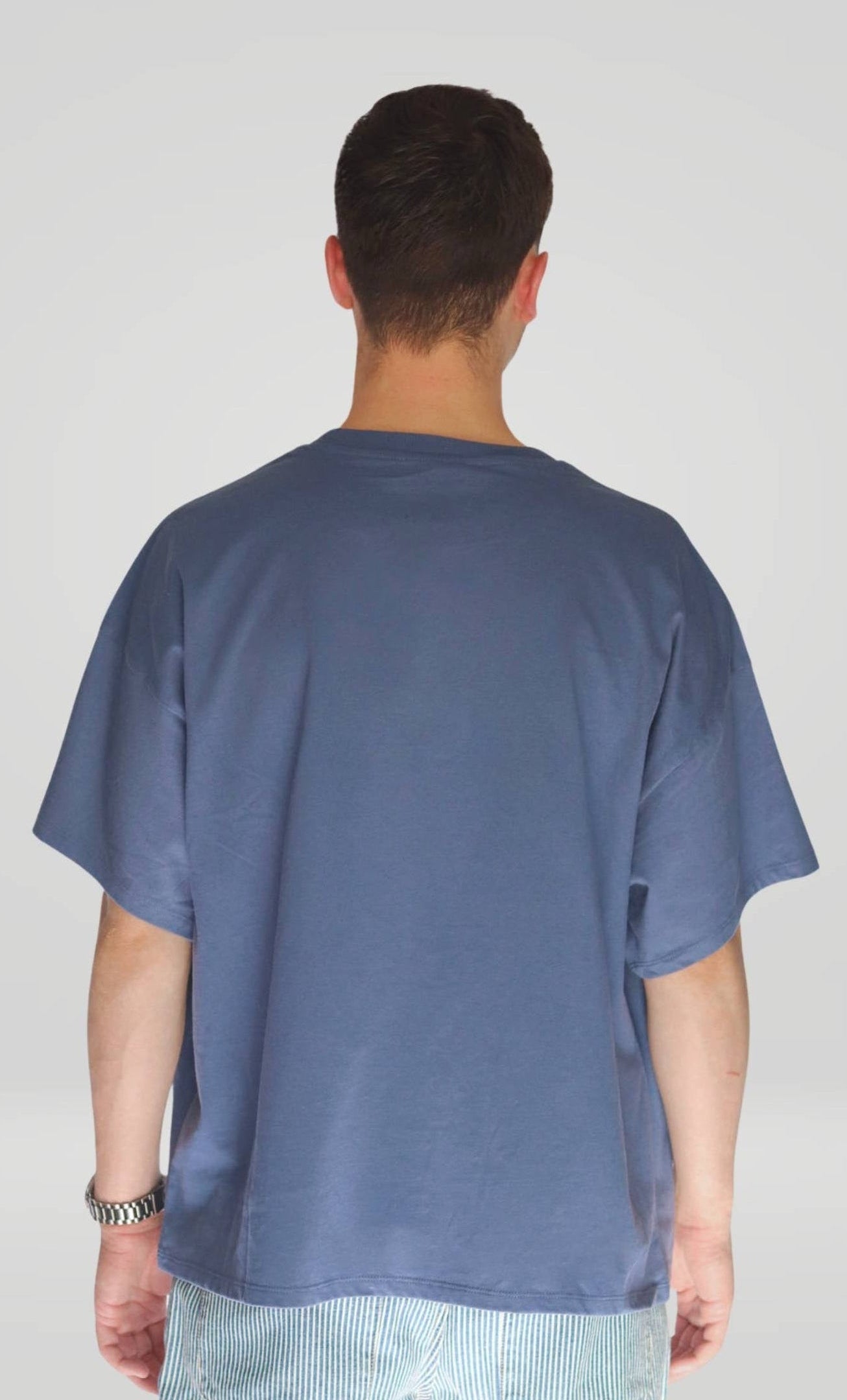 Person wearing a blue t-shirt from behind on a plain background