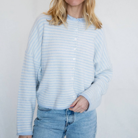 Woman wearing a light blue striped sweater and jeans against a white background