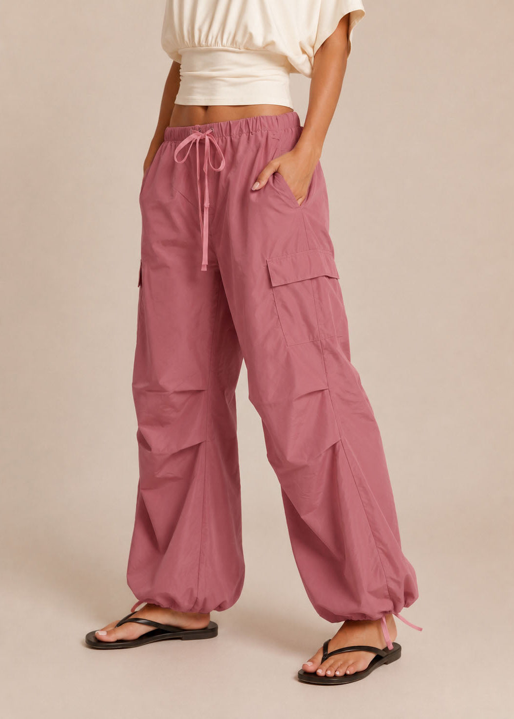 Person wearing pink cargo pants on a beige background