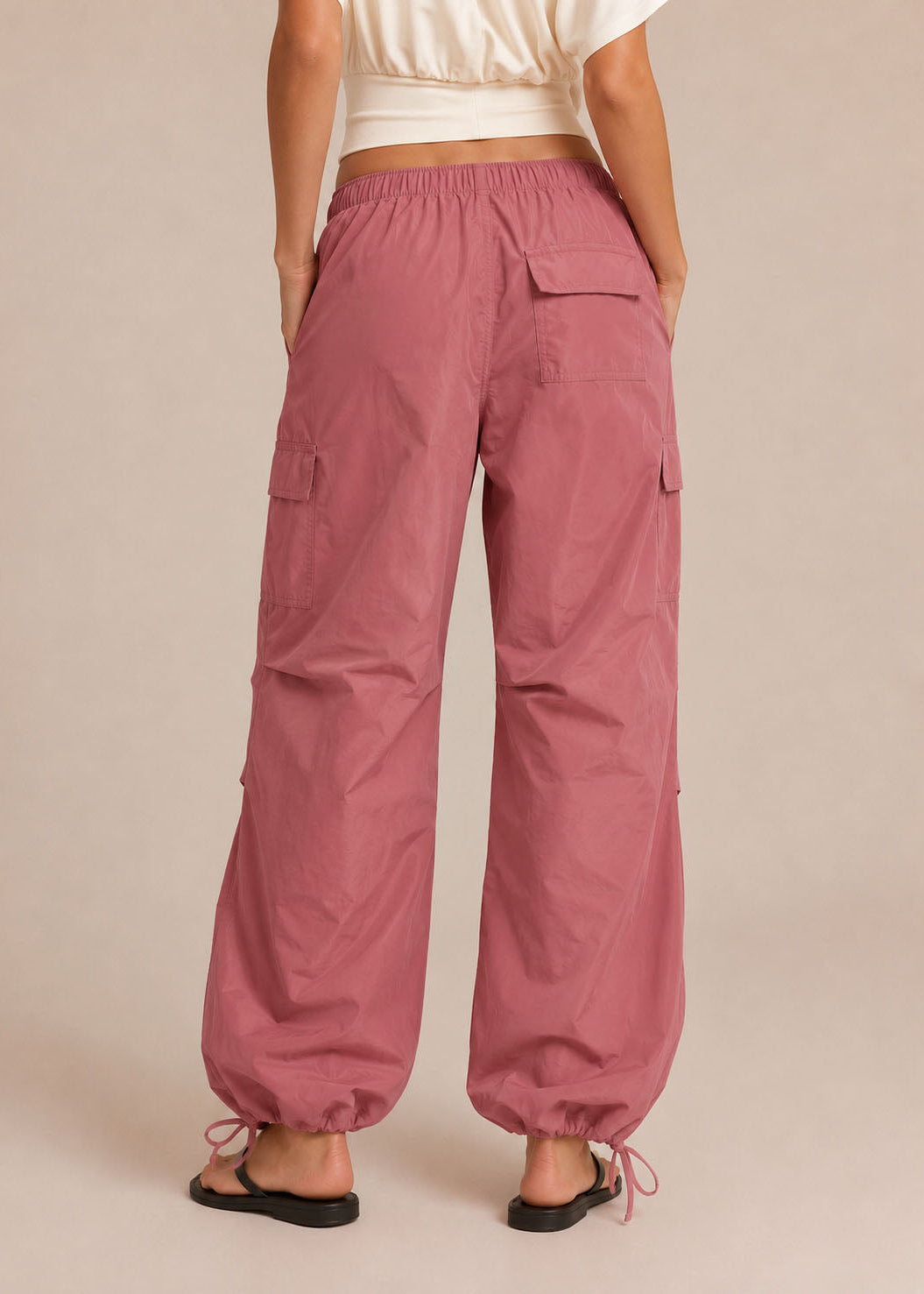 Person wearing pink cargo pants on a beige background