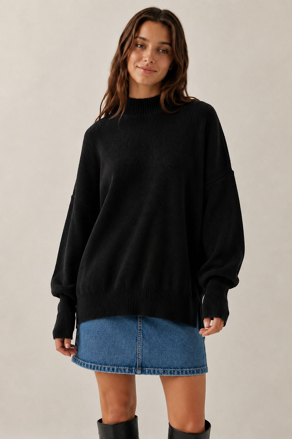 Woman wearing a black sweater and blue denim skirt on a plain background
