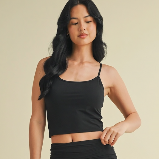 Woman wearing a black crop top and skirt against a beige background