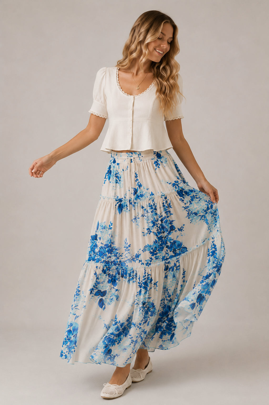 Woman wearing a white top and blue floral skirt on a plain background