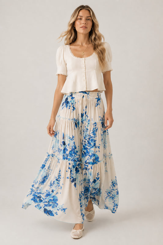Woman wearing a white top and blue floral skirt on a plain background