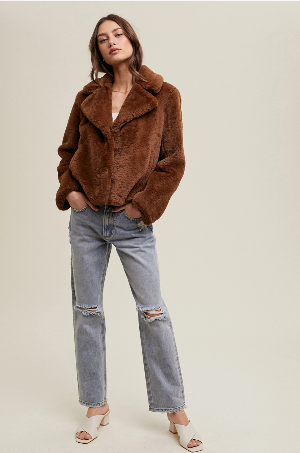 Women's chocolate brown faux fur jacket modeled with a relaxed fit, functional front buttons, and a flattering hip-length cut.