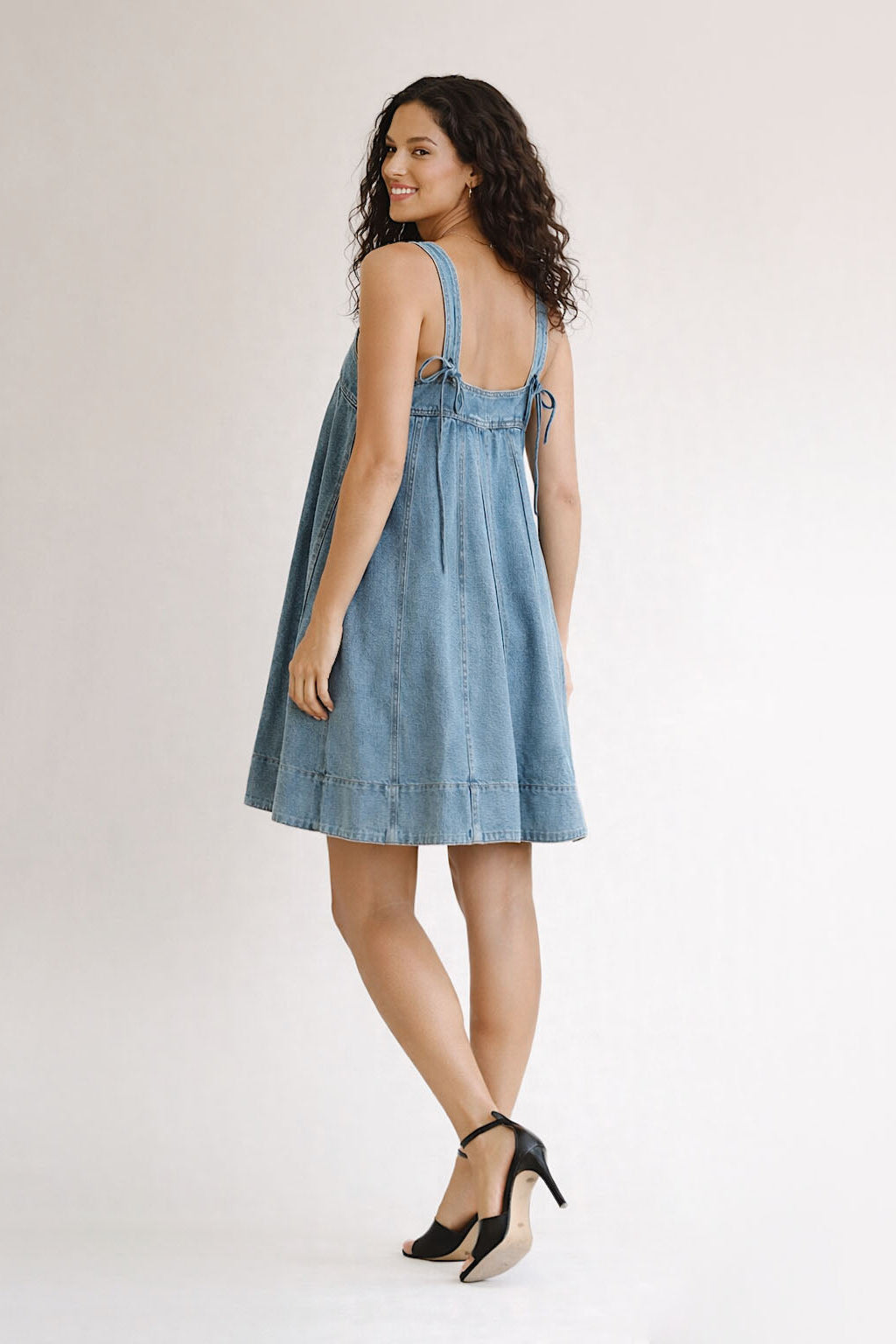 Woman wearing a blue denim dress on a white background