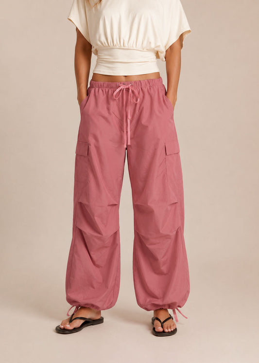 Person wearing pink cargo pants and a white top on a beige background