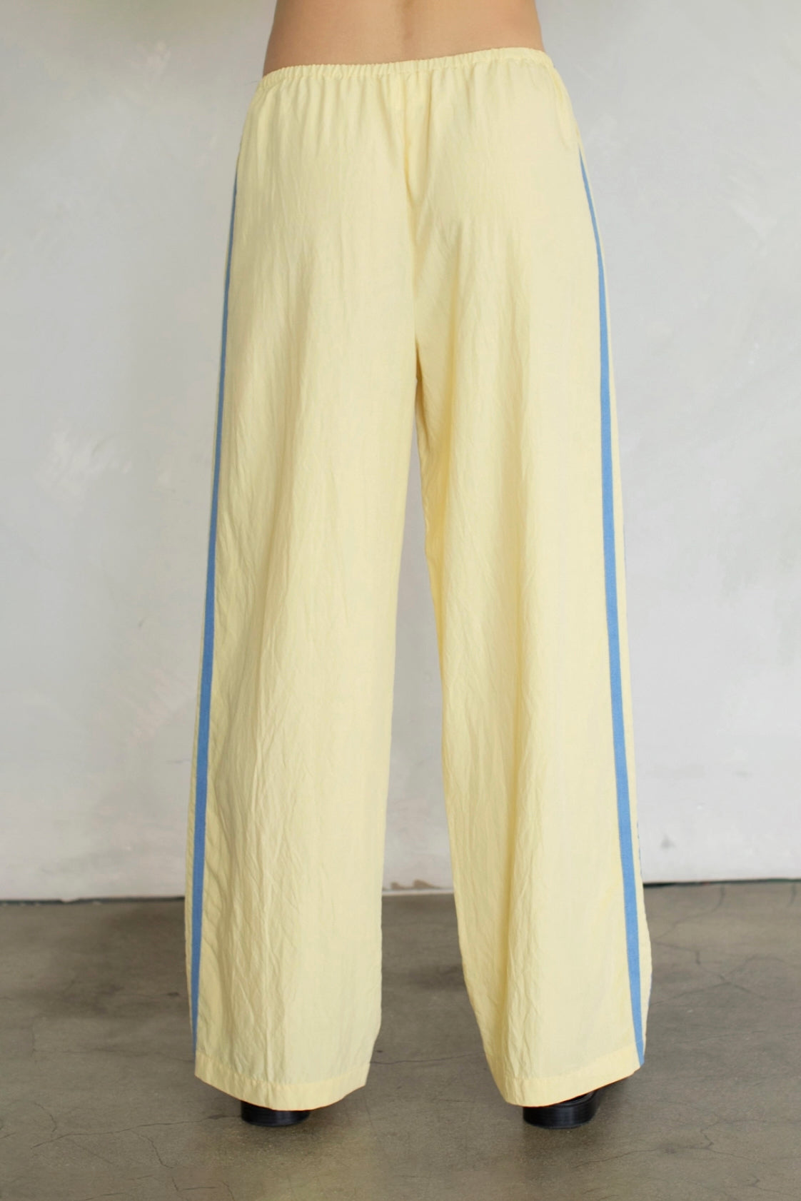 Yellow pants with blue side stripes on a plain background