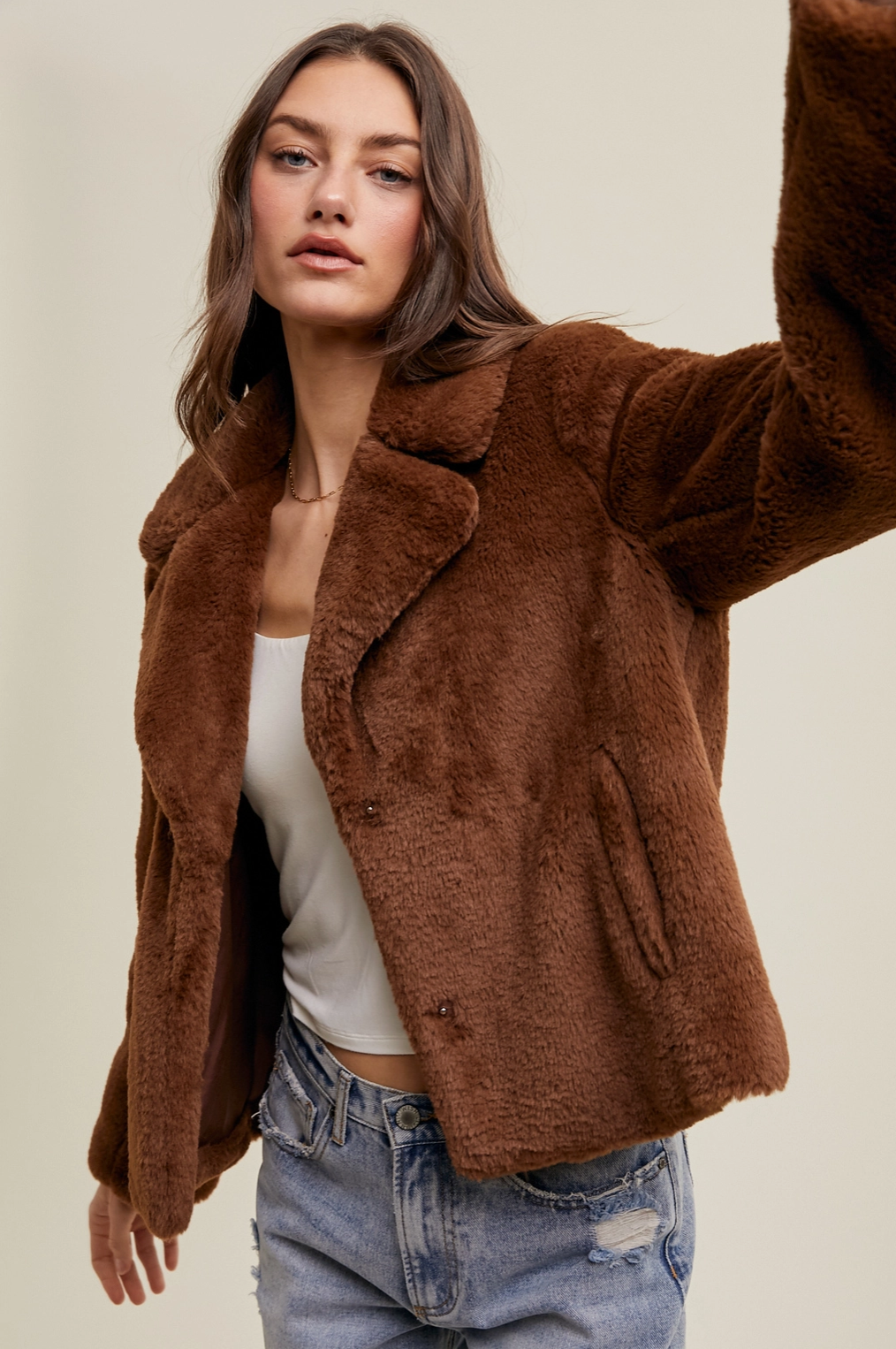 Woman modeling a rich chocolate brown faux fur coat with soft oversized texture, a classic collar, and cozy winter styling.