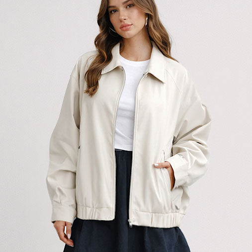 Woman wearing a beige jacket over a white shirt on a plain background