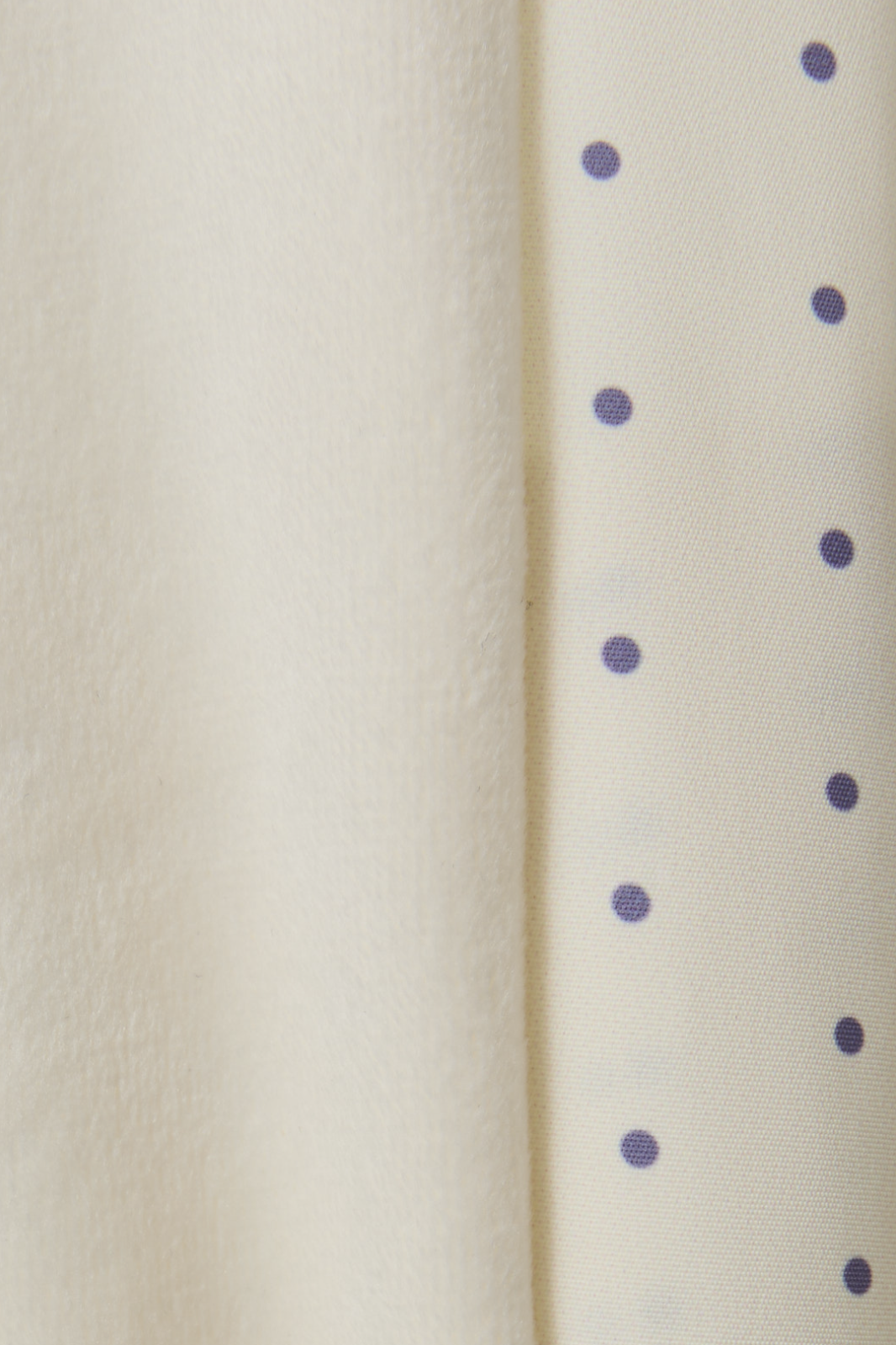 Close-up of a textured beige surface with small purple dots.