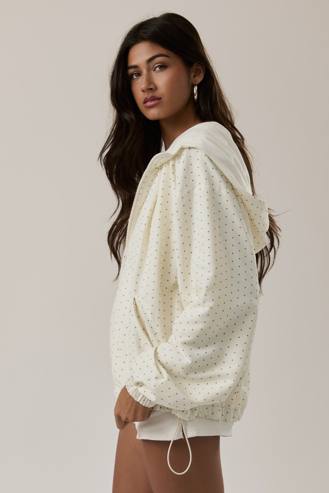 Woman wearing a cream-colored polka dot sweater against a plain background