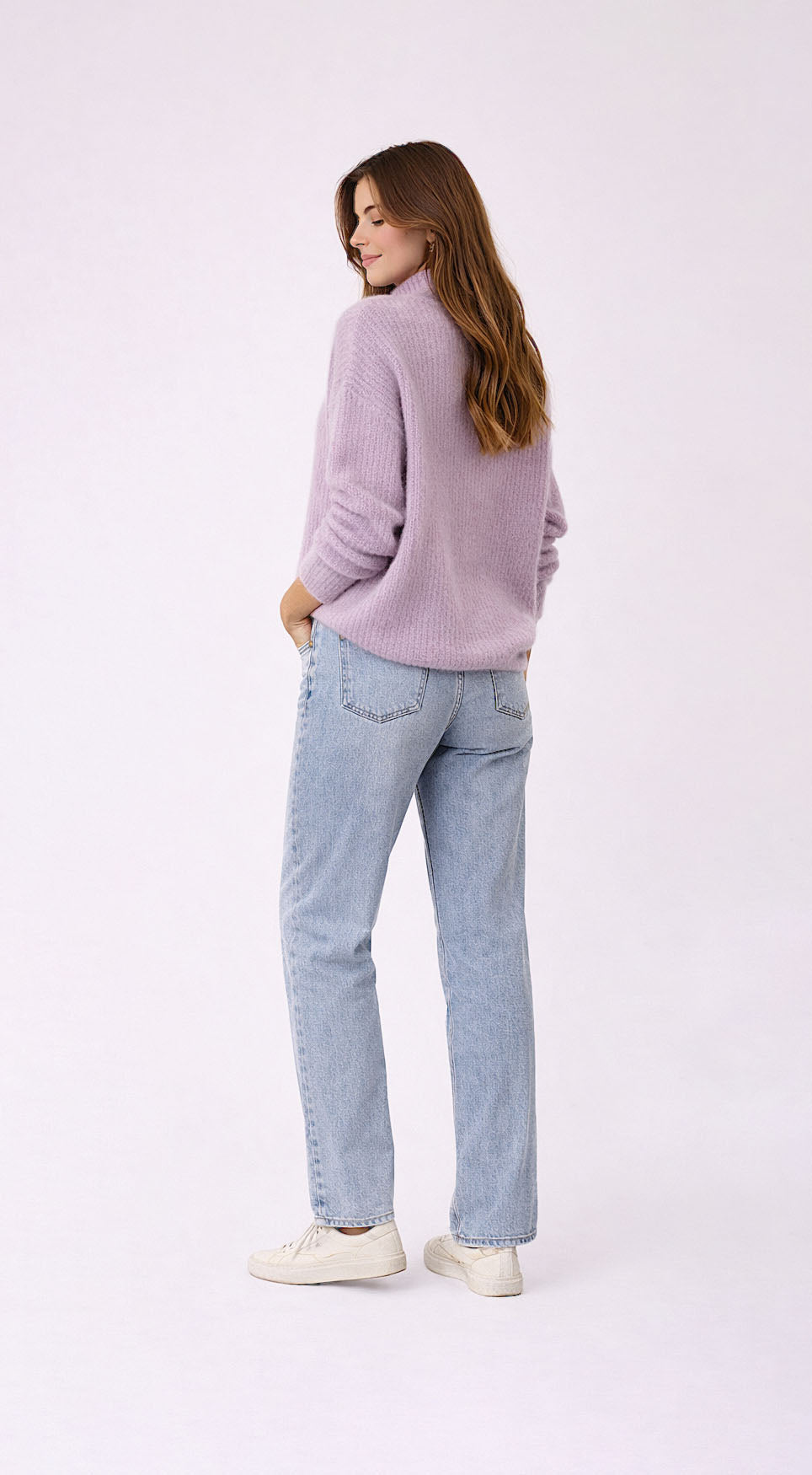 Woman wearing a light purple sweater and light blue jeans on a white background