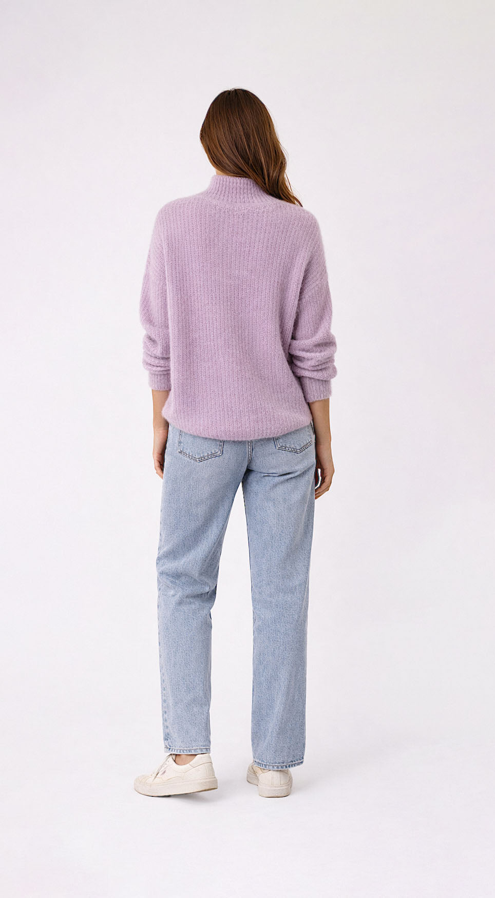 Person wearing a light purple sweater and light blue jeans on a white background