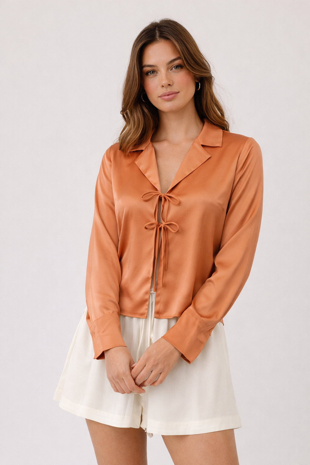 Woman wearing an orange satin blouse with a white background