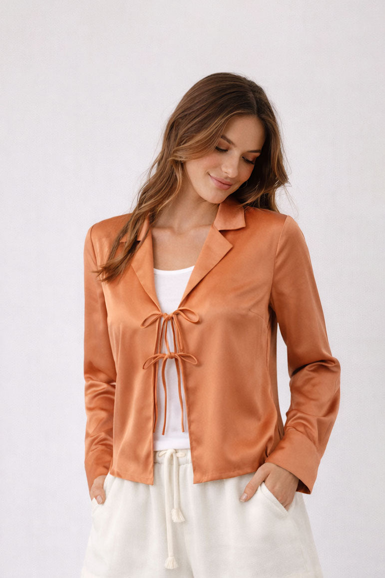 Woman wearing a rust-colored blouse with a white background