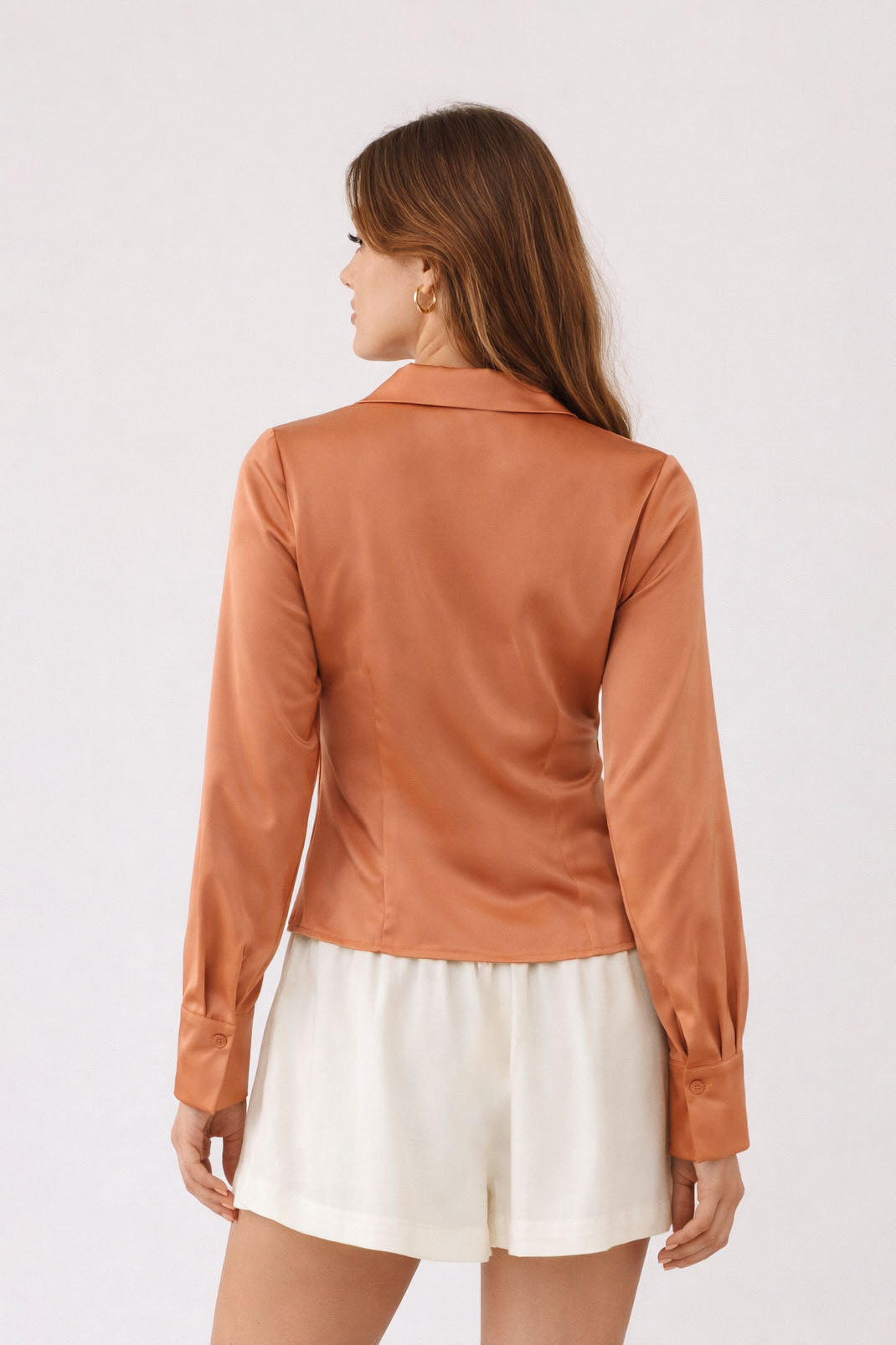 Woman wearing a brown leather jacket and white skirt on a light background