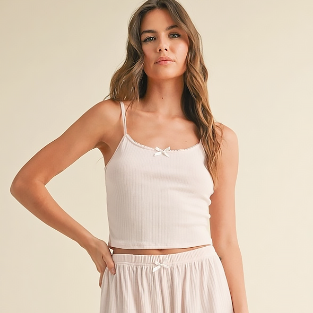 Woman wearing a white tank top and skirt on a beige background