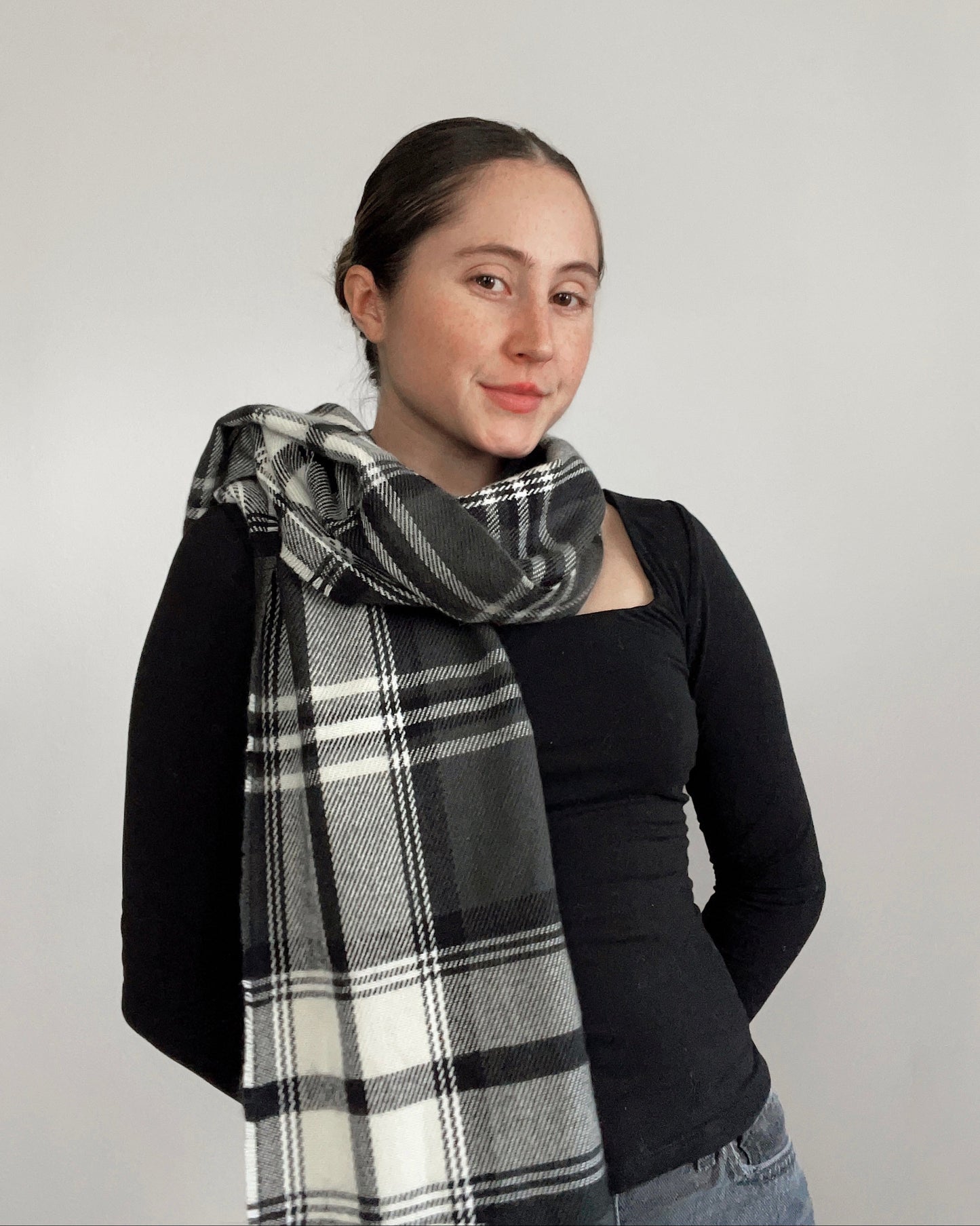 Woman wearing a black and white plaid scarf against a plain background