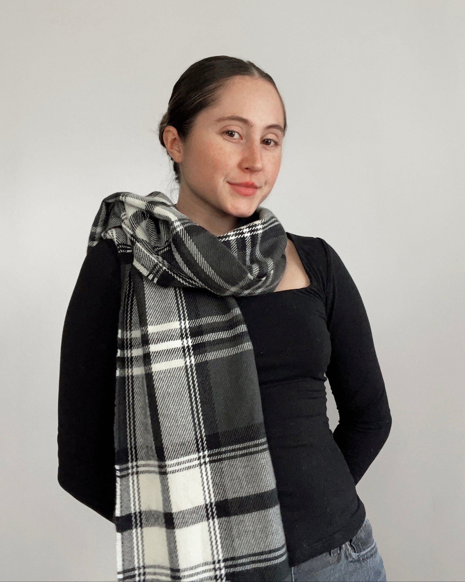 Woman wearing a black and white plaid scarf against a plain background