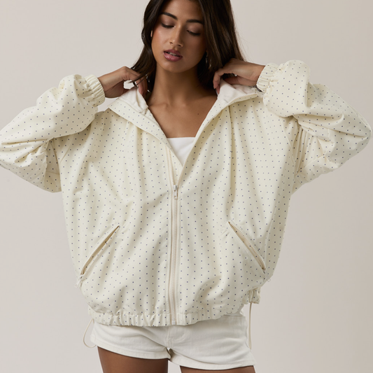 Woman wearing a cream-colored polka dot jacket on a plain background