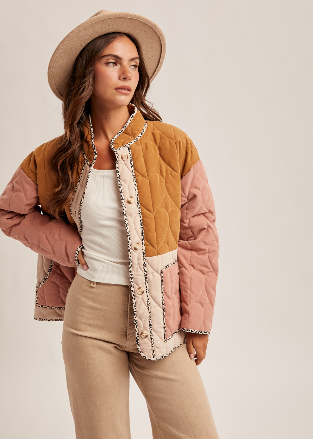 Woman wearing a colorful quilted jacket with a neutral background