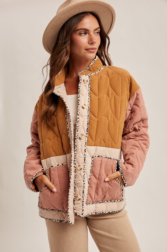 Woman wearing a patchwork quilted jacket with a beige hat on a plain background
