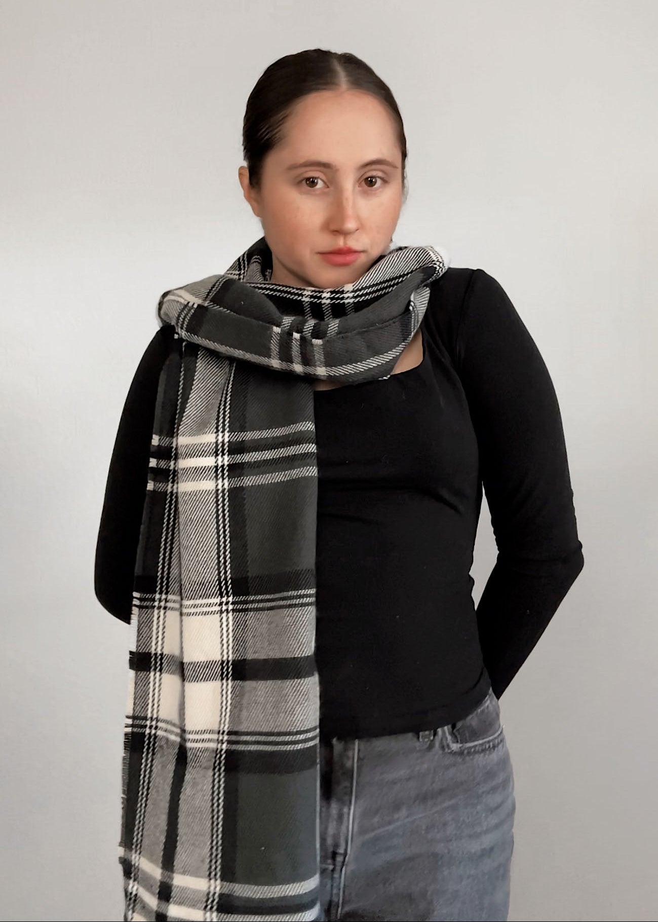 Woman wearing a large plaid scarf against a plain background