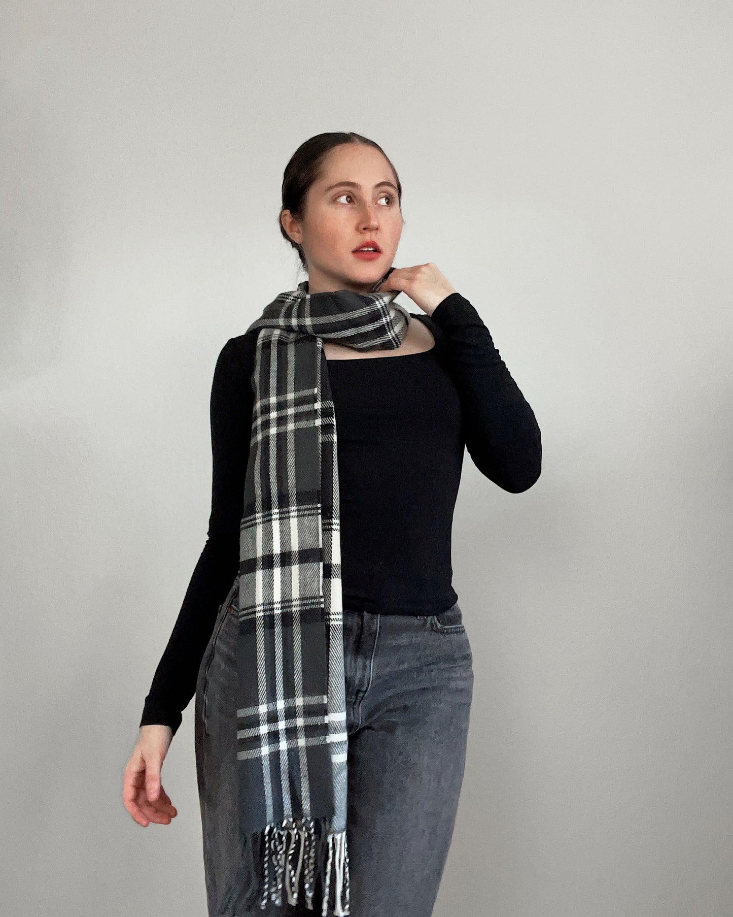 Woman wearing a black and white plaid scarf against a plain background