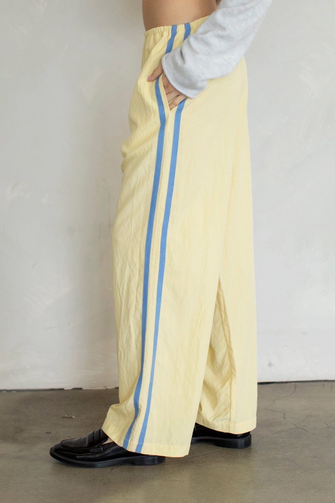 Person wearing yellow pants with blue stripes against a plain background