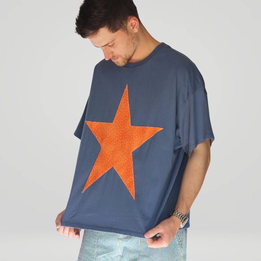 Man wearing a blue t-shirt with an orange star on a plain background