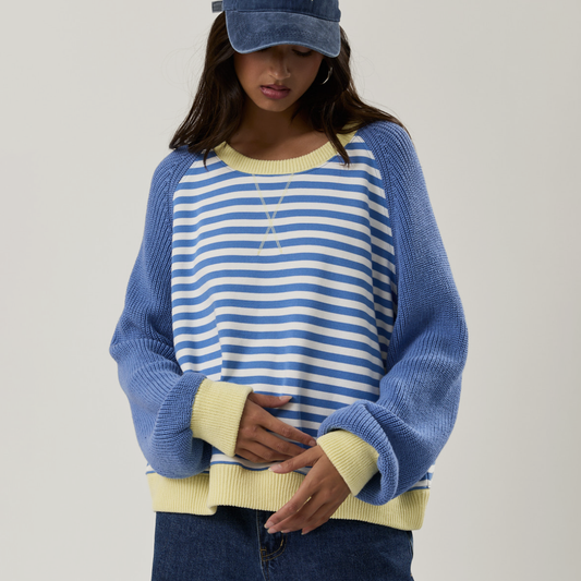 Person wearing a blue and white striped sweater with yellow accents on a plain background