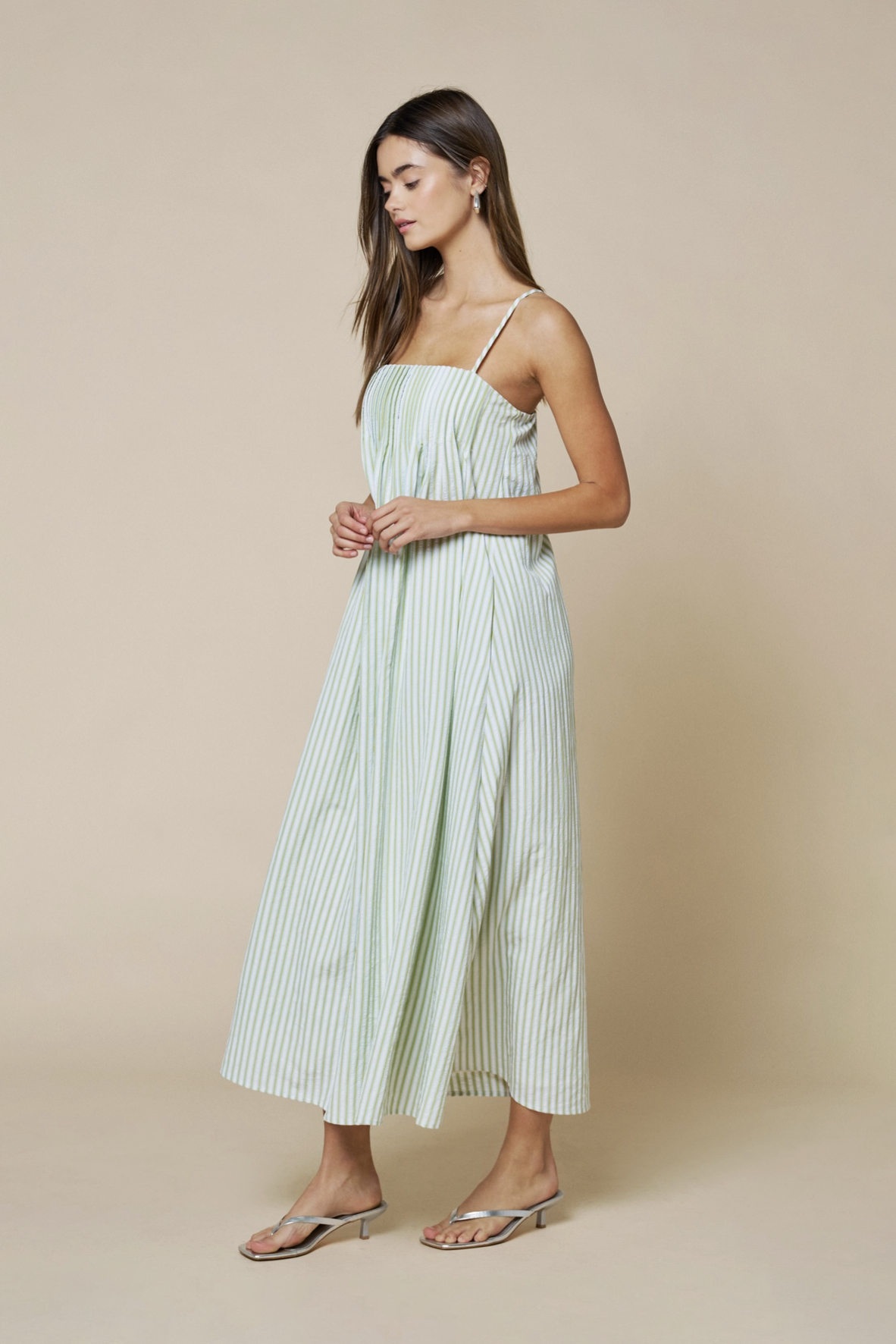 Woman wearing a light green striped dress against a beige background