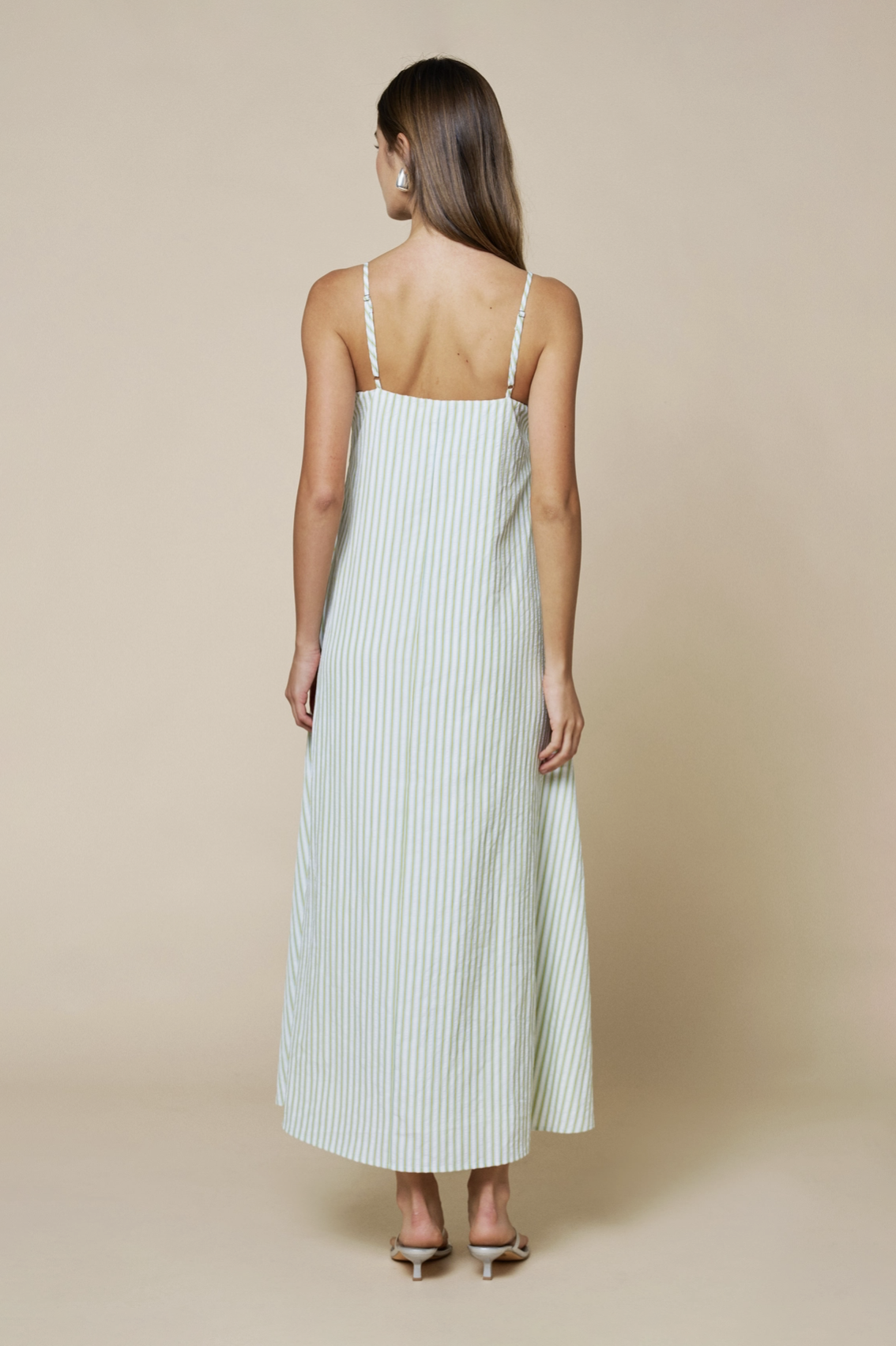 Woman wearing a white dress with thin straps on a beige background