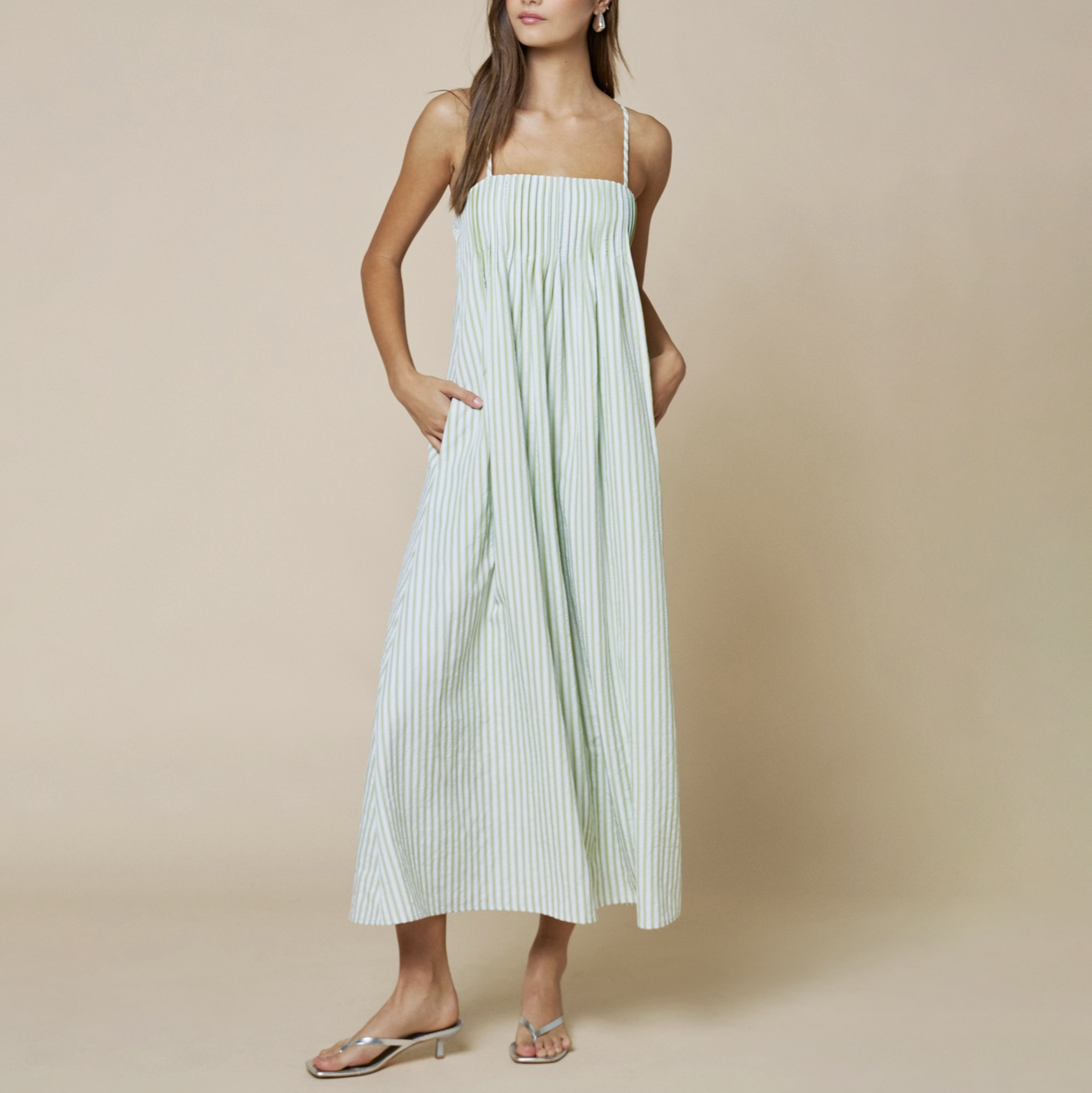 Woman wearing a light green striped dress against a beige background