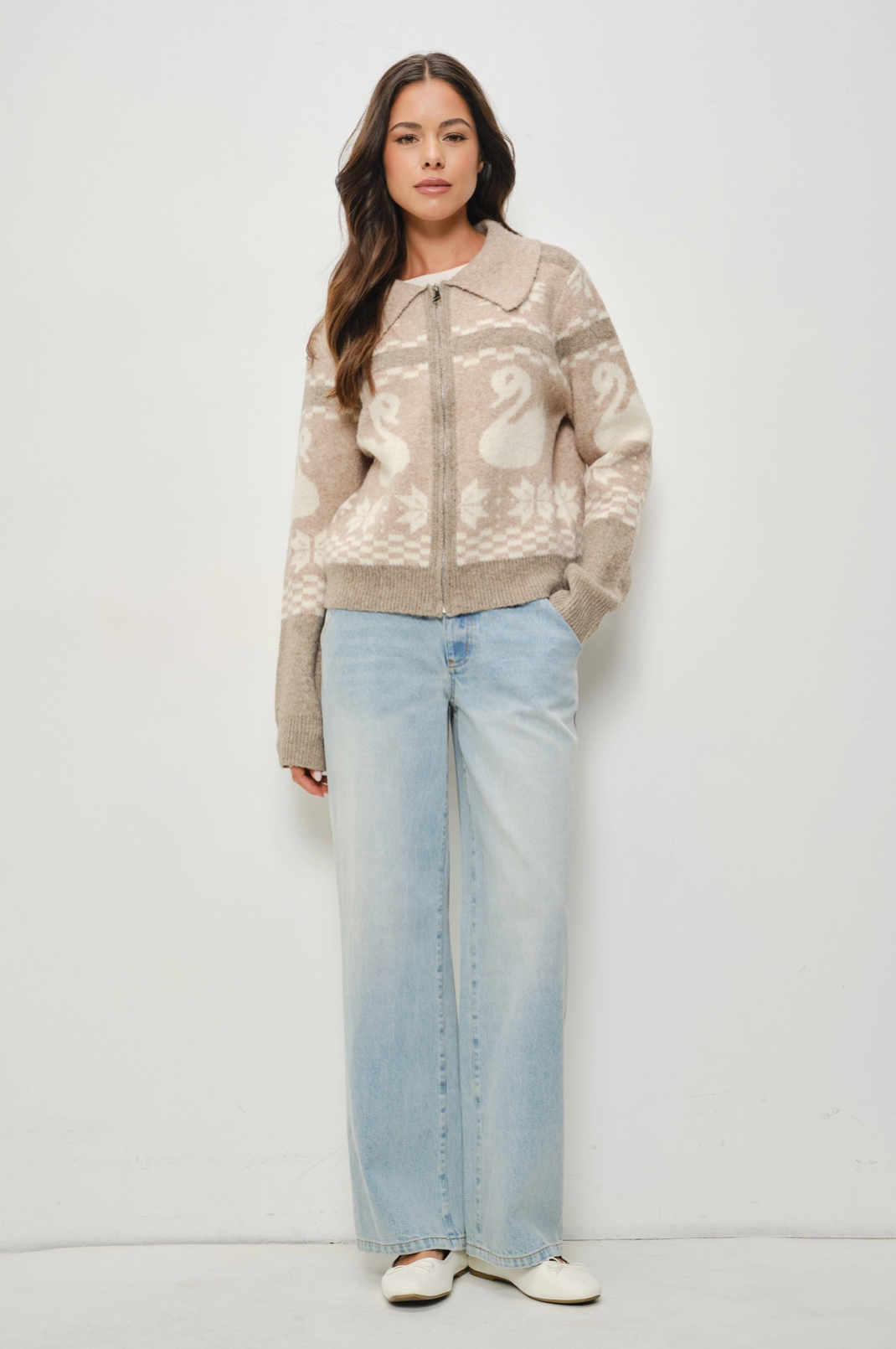 Woman wearing a patterned jacket and light blue jeans on a white background