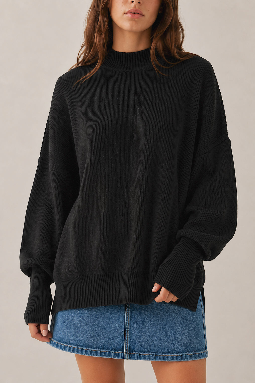 Person wearing a black sweater and denim skirt on a neutral background