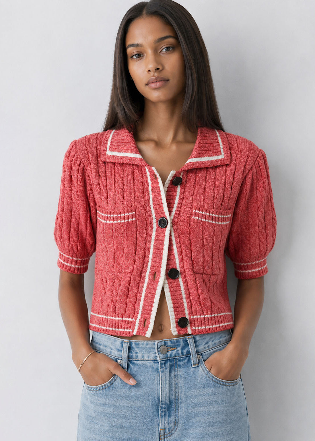Woman wearing a red textured jacket with white trim against a plain background