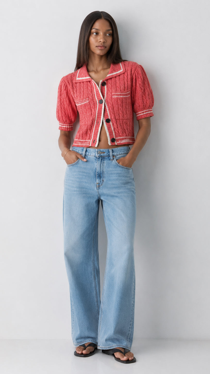 Woman wearing a red jacket and light blue jeans against a white background