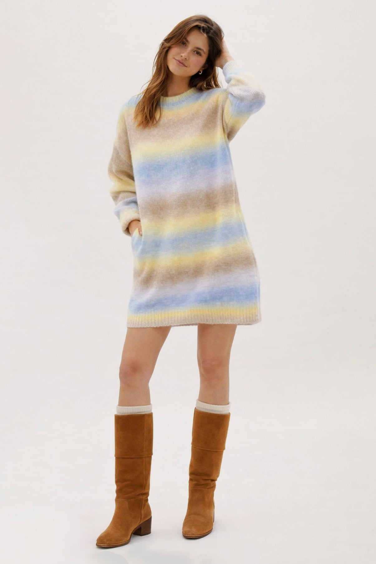 Woman wearing a striped sweater dress with brown knee-high boots on a white background